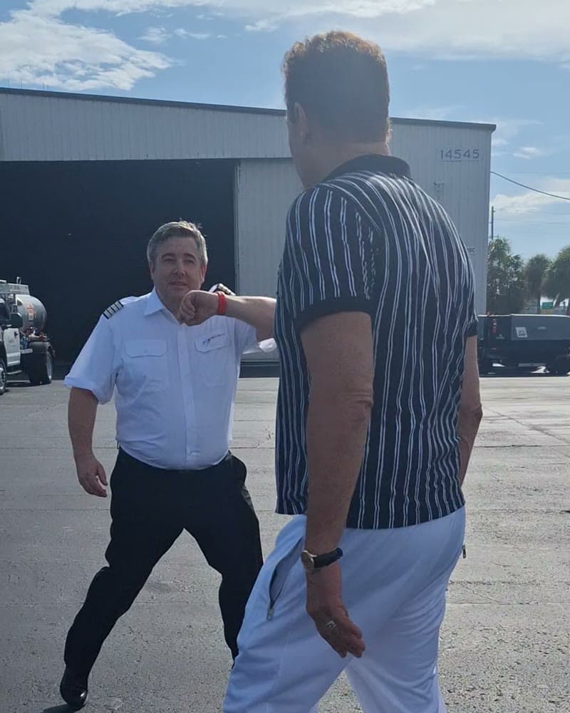 Tom Cummins greeting his pilot on the tarmac outside a hangar