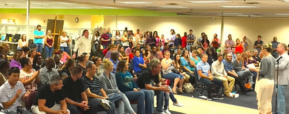 Tom Cummins addressing a packed employee meeting on the call center floor.