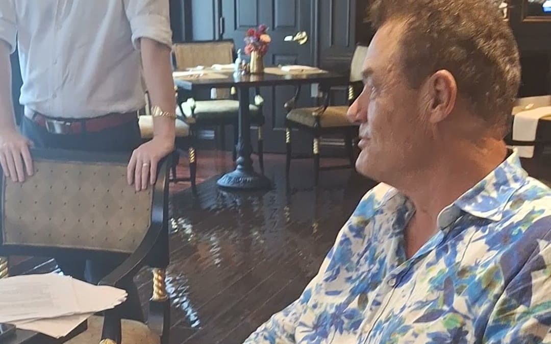 Tom Cummins in conversation at a dinner table in Italy.