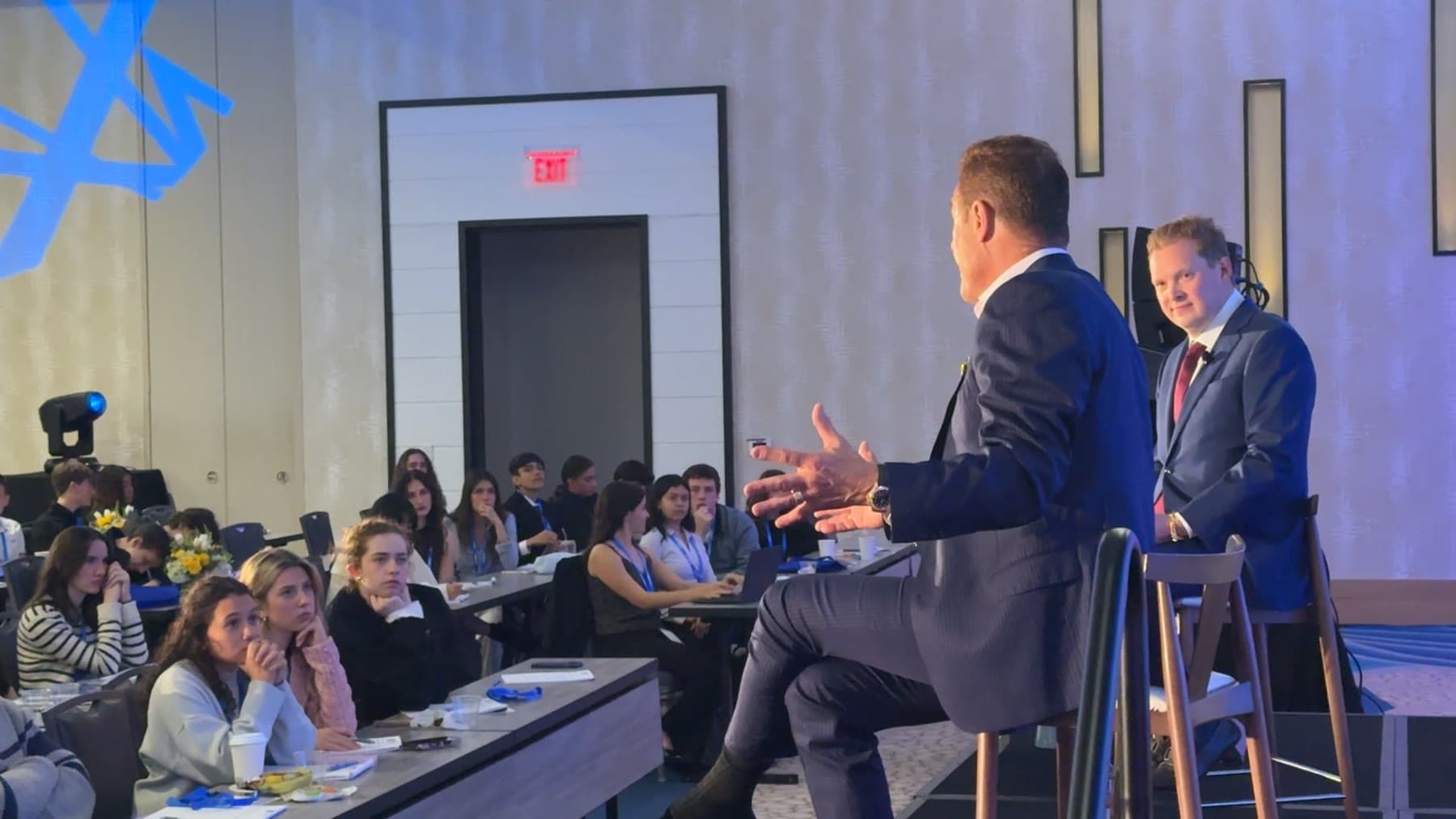 Tom Cummins leaning toward his audience mid explanation at a conference.
