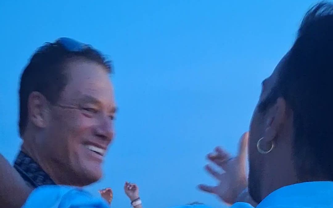 Tom Cummins greeting a guest with open arms at an evening event.