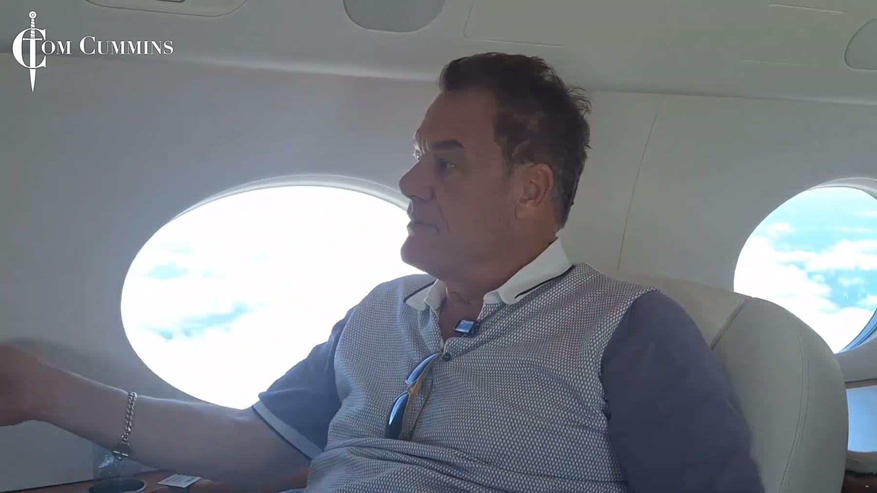 Tom Cummins gazing out an oval window in a private jet cabin.