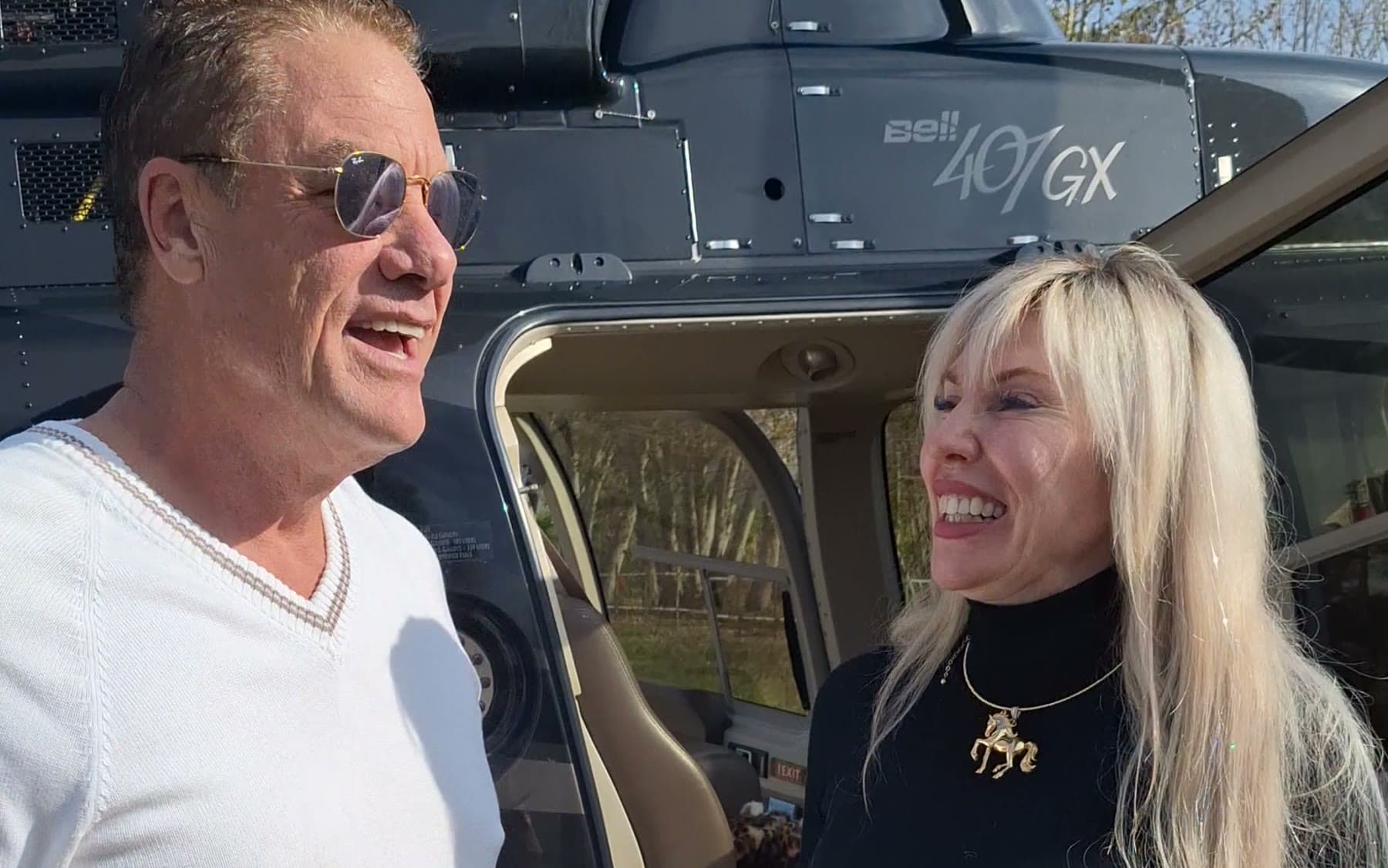 Tom Cummins sharing a laugh beside a helicopter in the Tuscan countryside.
