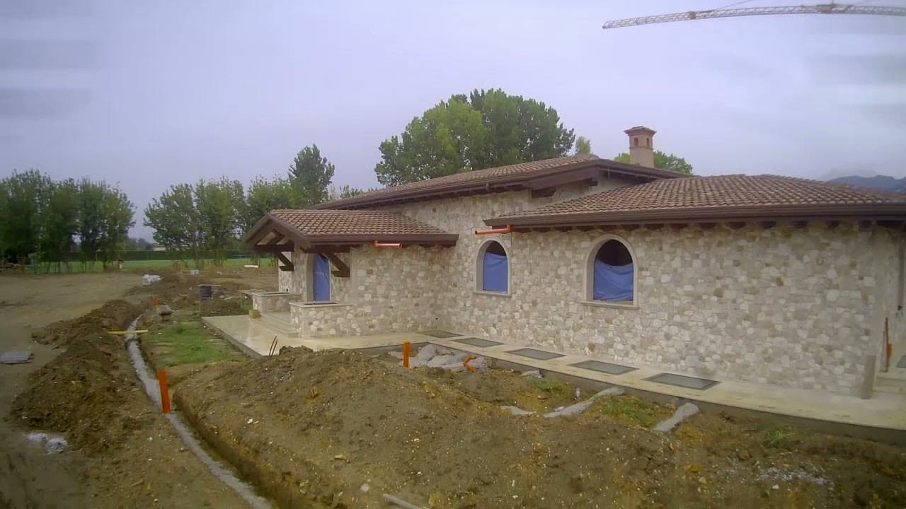 Tom Cummins's stone villa mid construction under a crane and open sky.