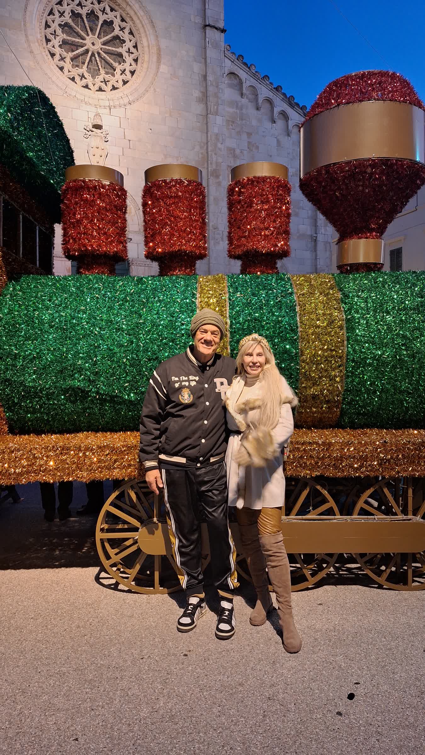 Tom and Victoria smiling in front of the giant Christmas train in Pietrasanta