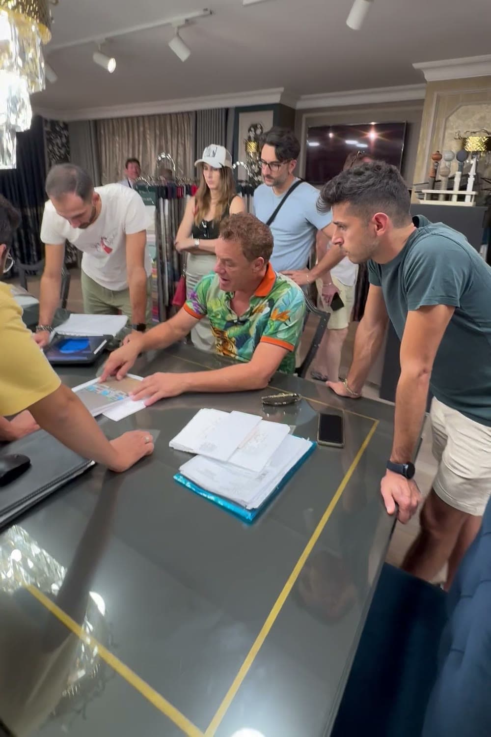 Tom at the center of a showroom table in Istanbul, walking his team through the numbers as five people lean in