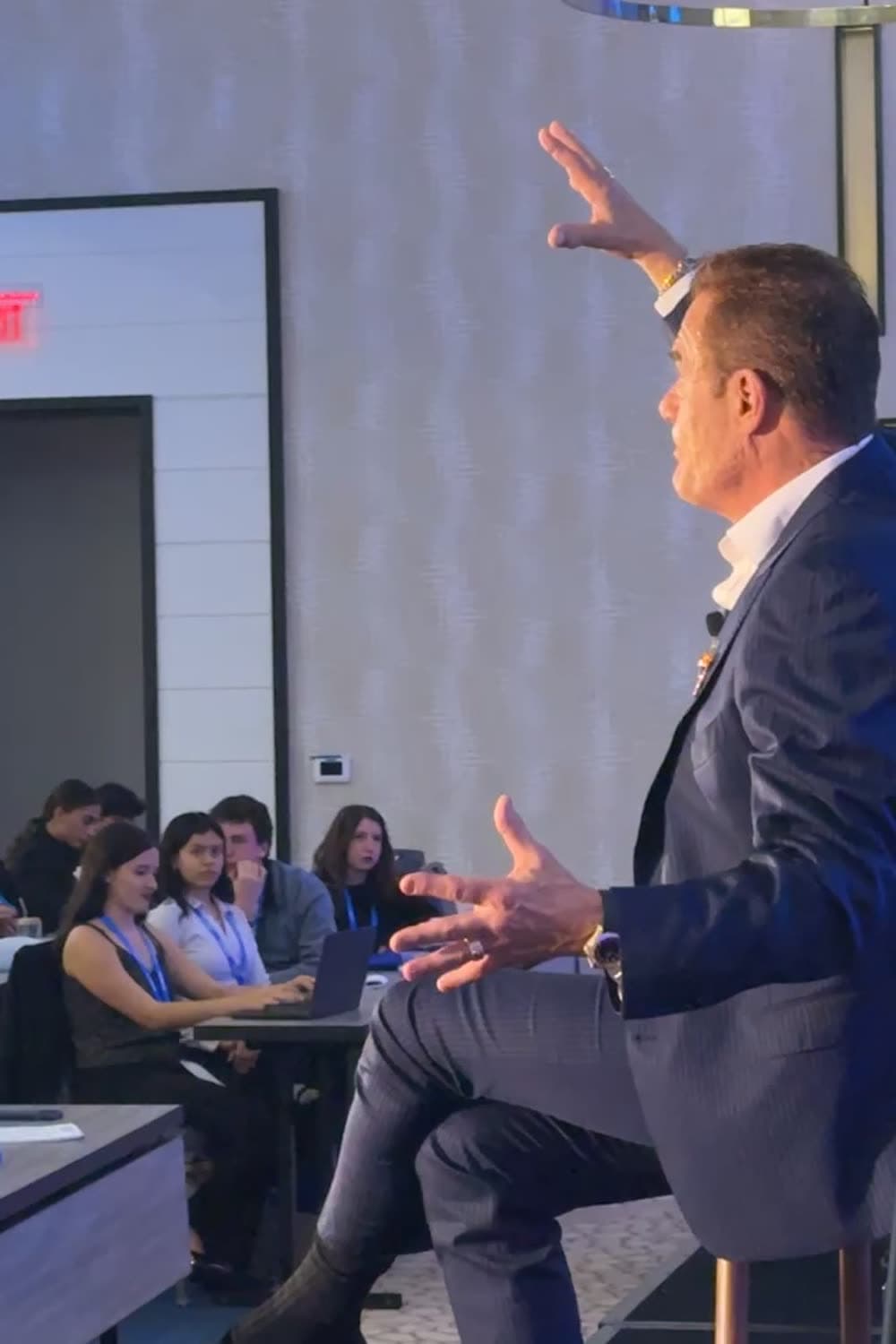 Tom on stage at TigerCon with raised hands over a full room of attendees