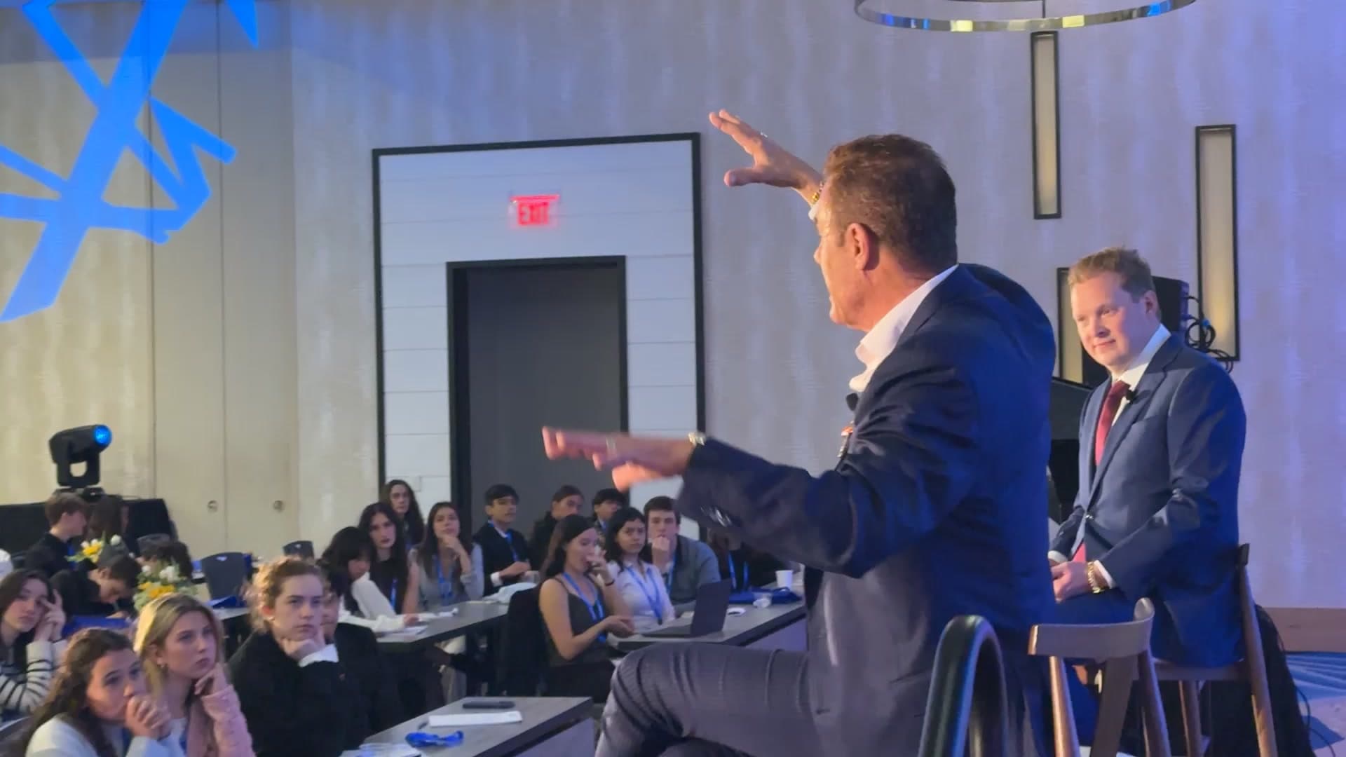 Tom on stage mid-gesture in front of a seminar audience at TigerCon