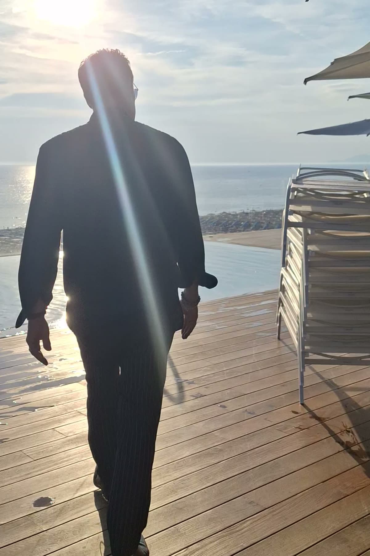 Tom silhouetted against the low sun on a rooftop pool deck above Viareggio beach