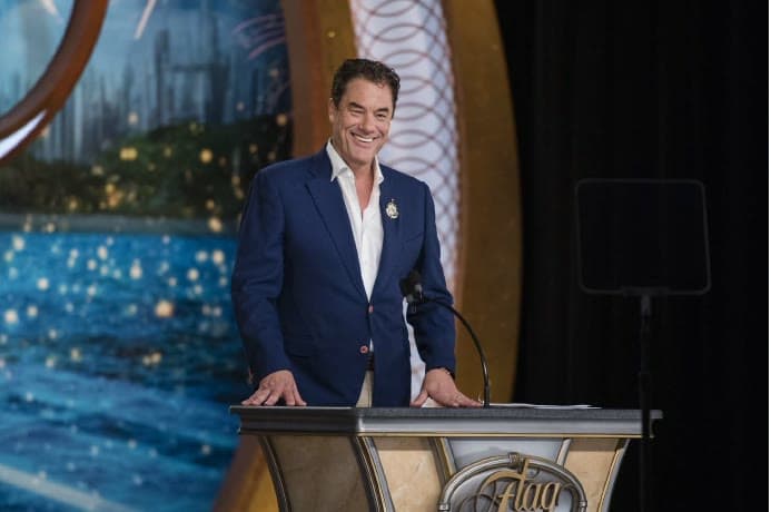 Tom Cummins smiling behind an ornate podium while addressing guests at an evening gala.