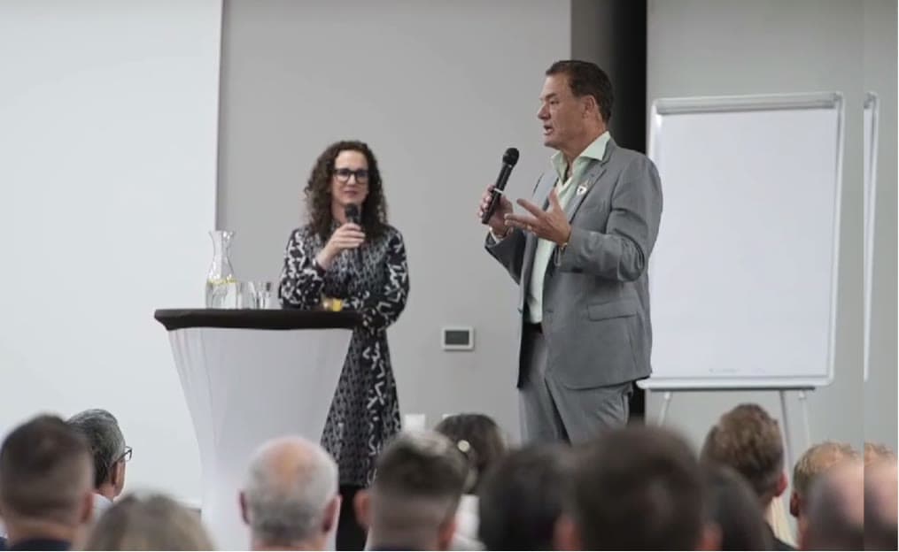 Tom Cummins coaching a business workshop with a handheld microphone.